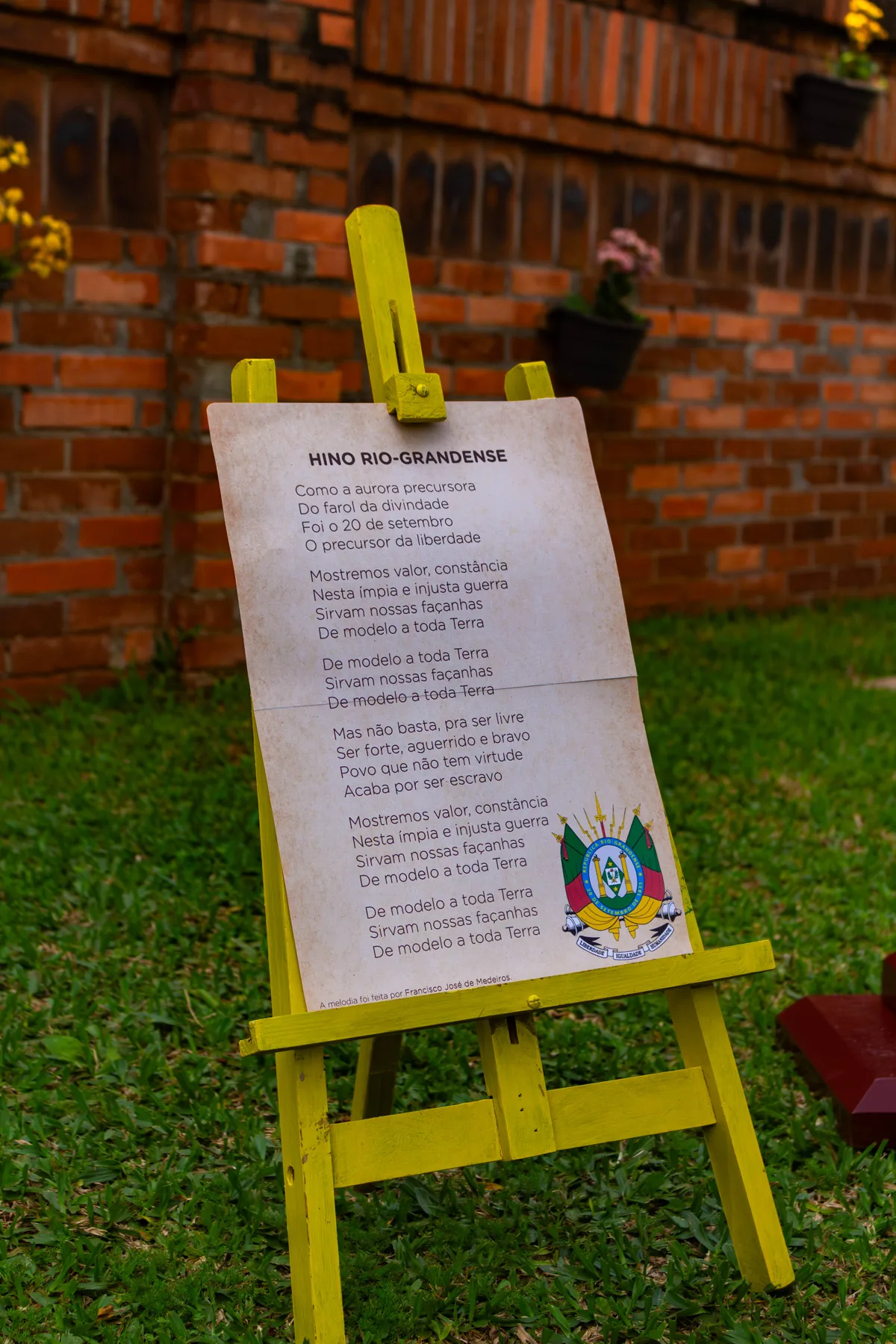 Letra do Hino Rio-Grandense apoiada em um cavalete ao ar livre